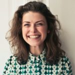 Woman headshot in green and white shirt smiling