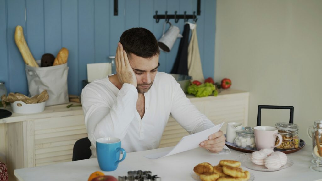 Man reviewing a confusing medical bill at his kitchen table