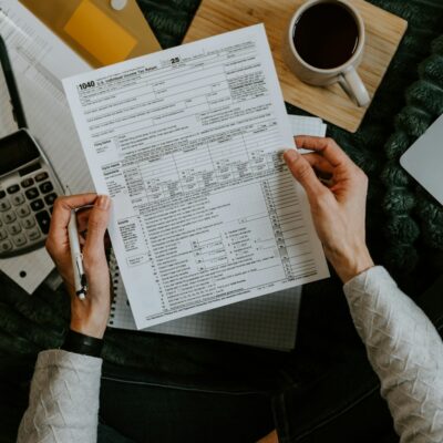 Hands holding billing forms beside a calculator and laptop Hands holding billing forms beside a calculator and laptop