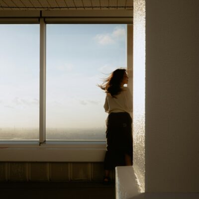California sexual abuse and assault claims Woman looking out a window at sunset - California sexual abuse and assault claims